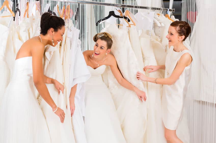 women having fun during bridal dress fitting in shop